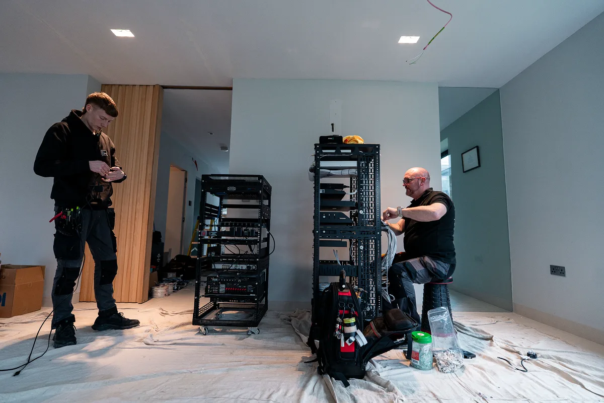 Two Ribble AV engineers building and patching control racks in a house at second fix