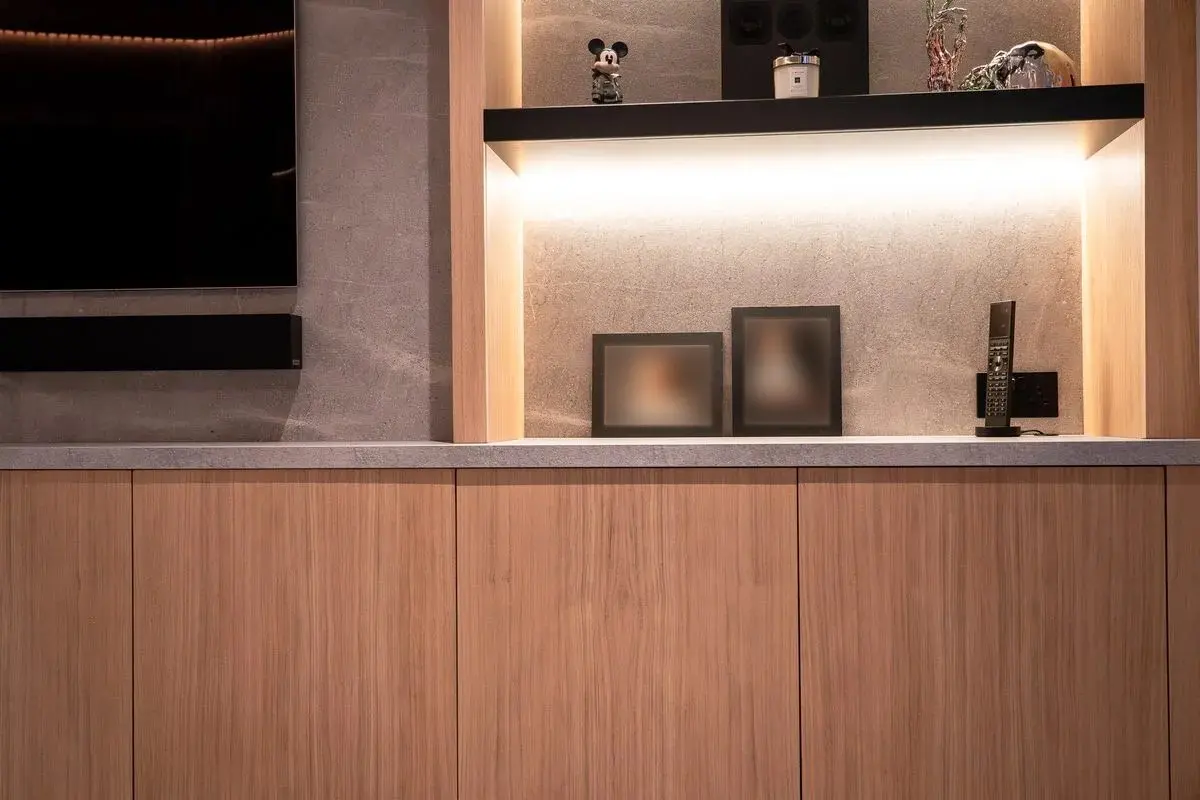 Lit shelving above the oak cabinetry, with the system remote on the stone worktop
