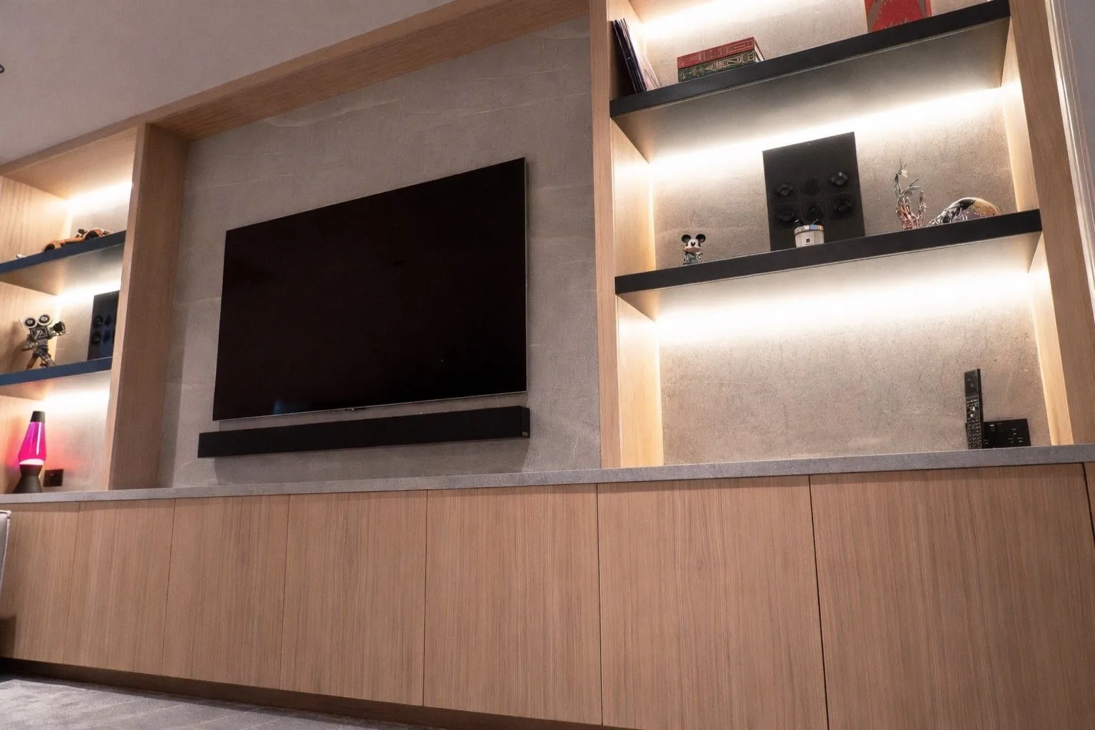 The full length of the wall, with speakers set into the shelving on both sides
